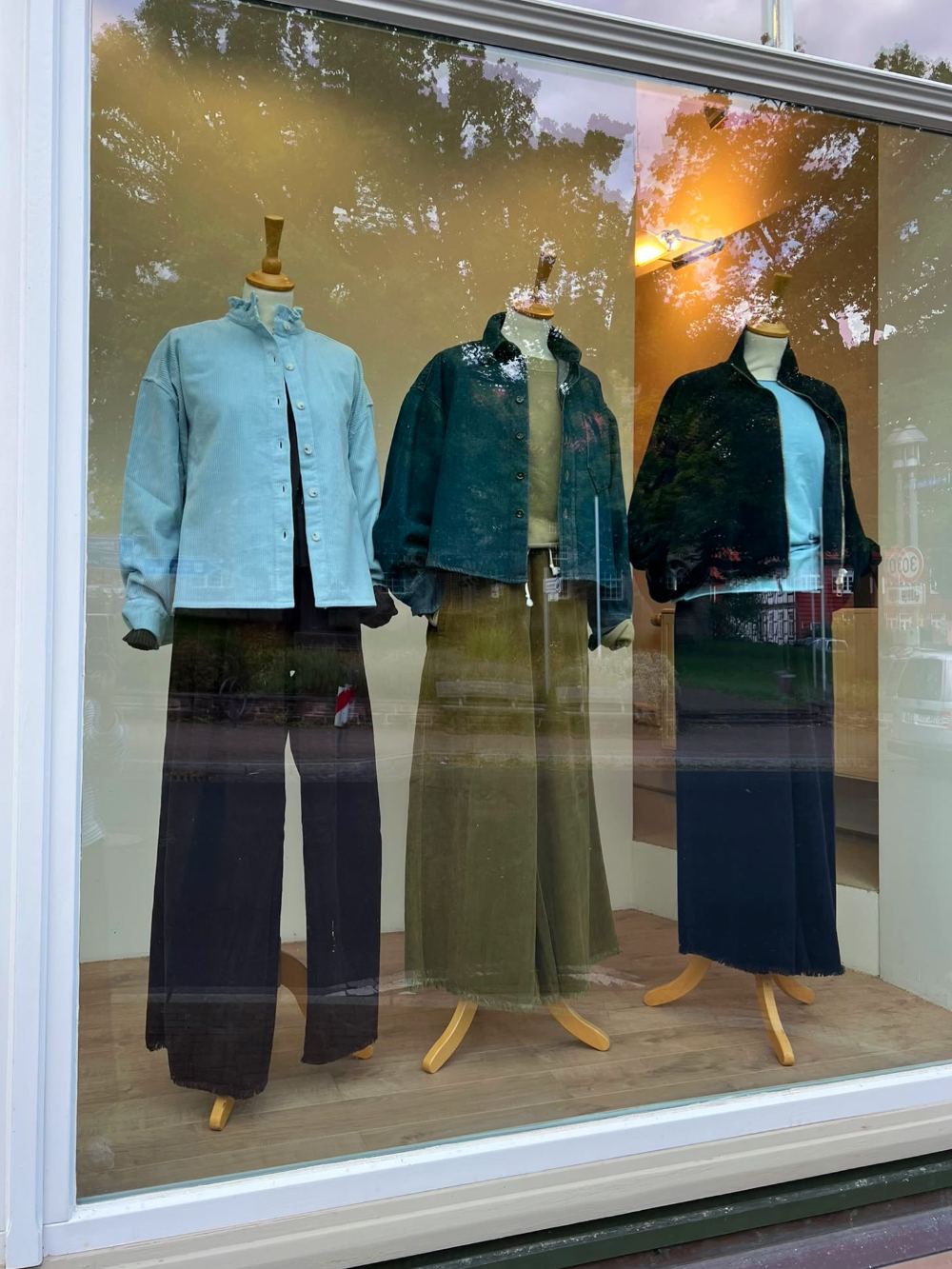Schaufenster von ELLA mit drei Puppen in Jacken und weiten Hosen