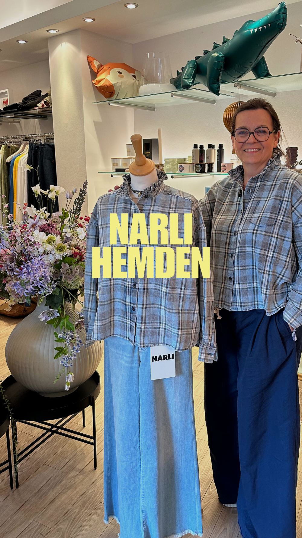 Ella im Laden in einem karierten NARLI-Hemd, daneben dieselbe Bluse auf einer Schaufensterpuppe